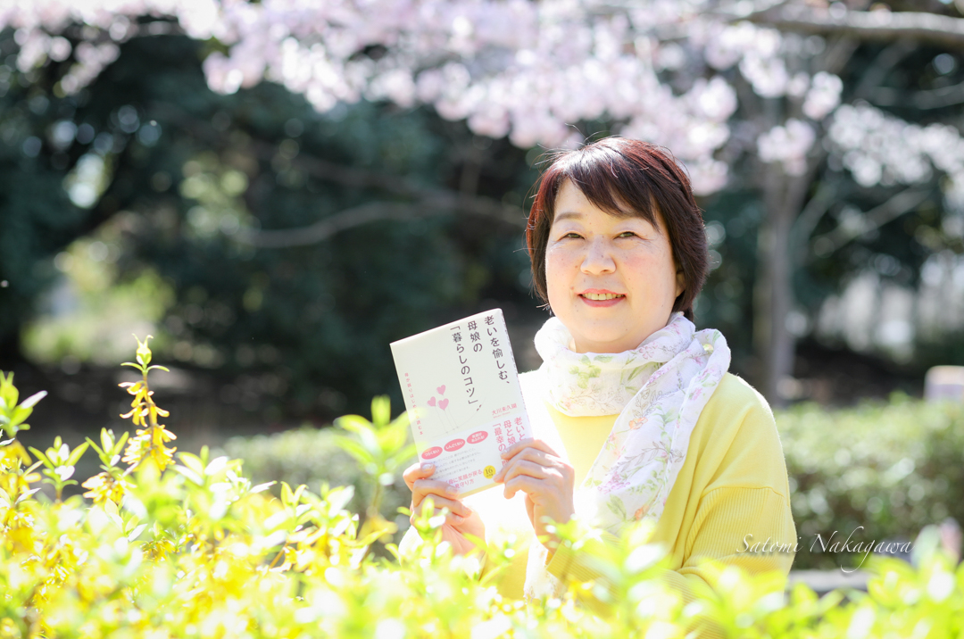 桜の花と本を持った笑顔の女性