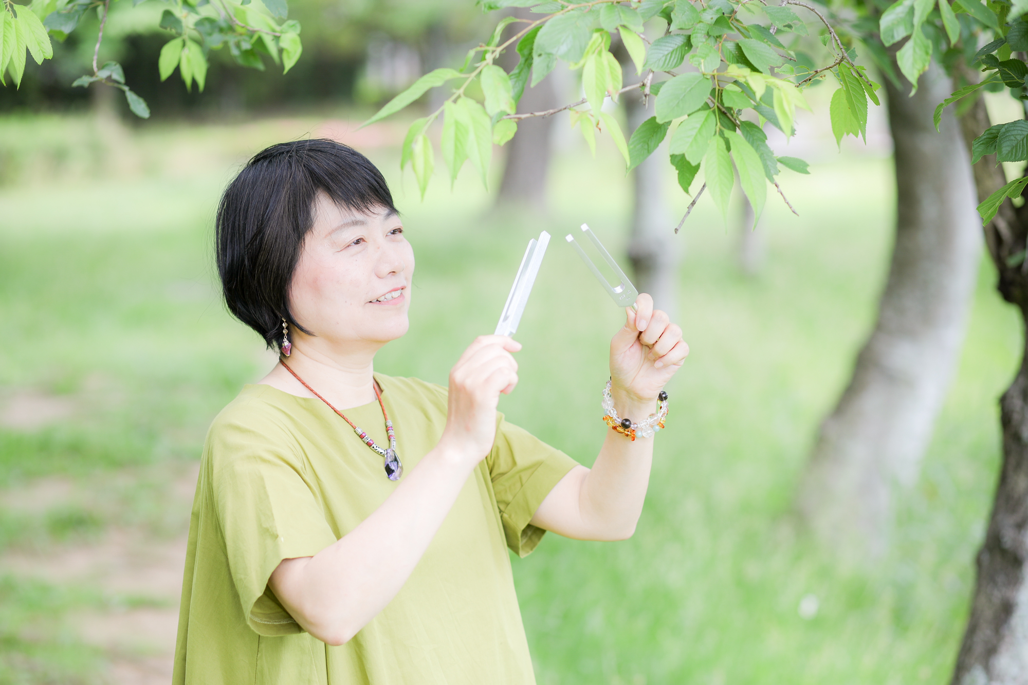 緑の中で音叉を鳴らす女性