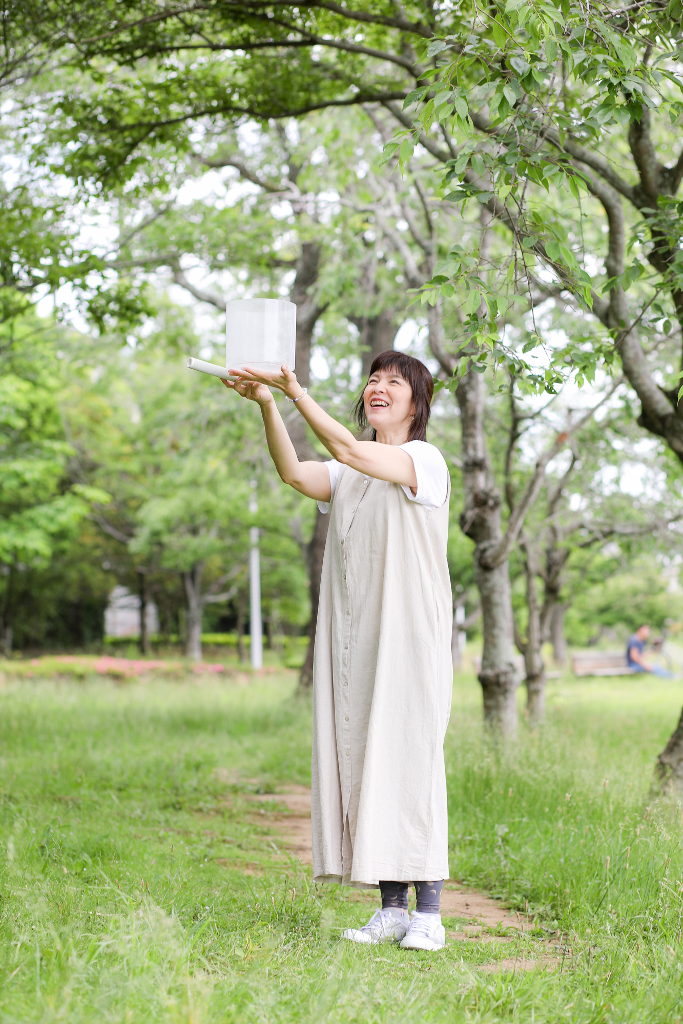緑の中でクリスタルボウルを掲げる女性