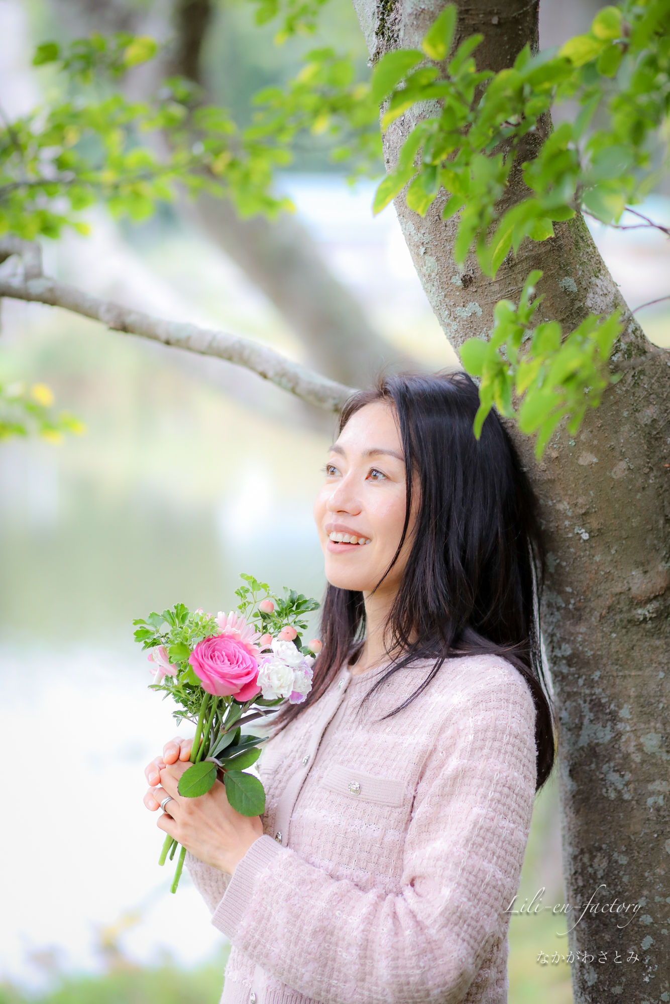 気にもたれかかるブーケを持った女性