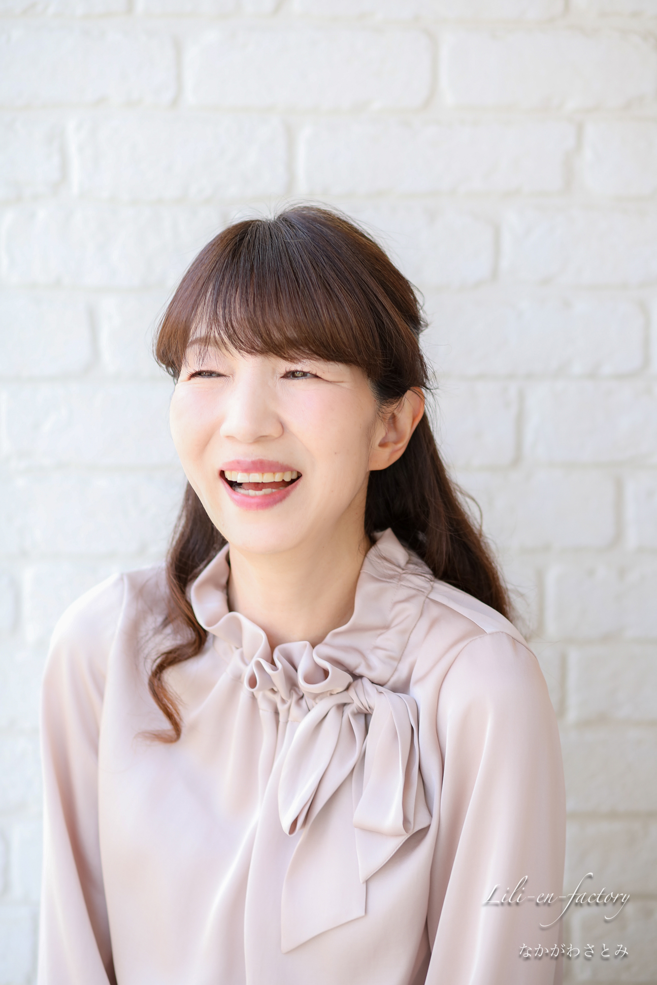 白壁の前で笑顔の女性