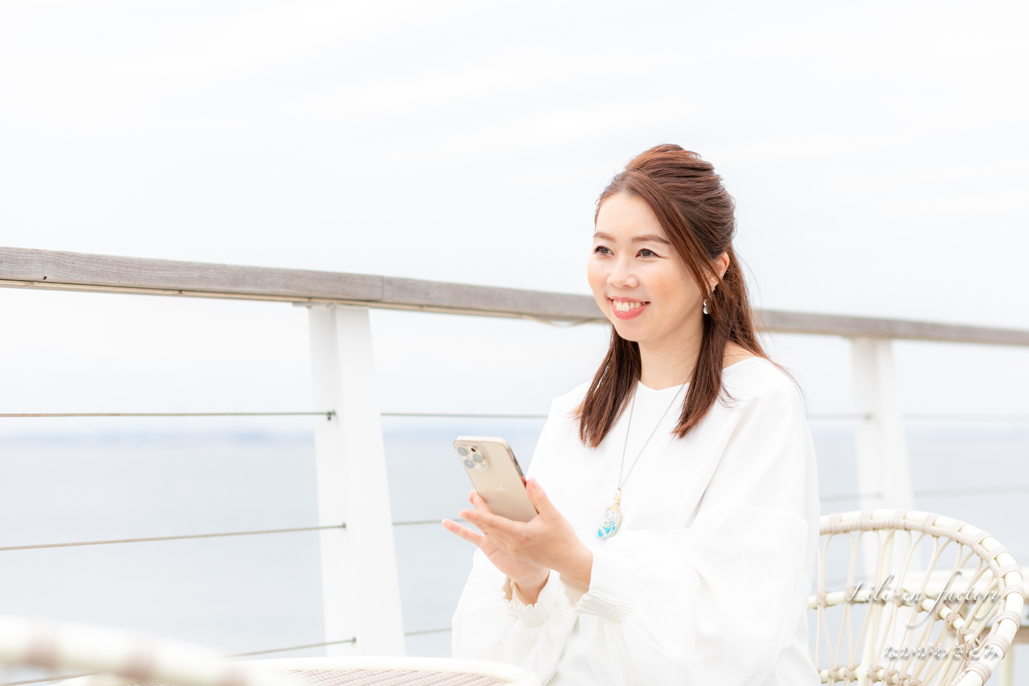 海辺でスマホを触る女性