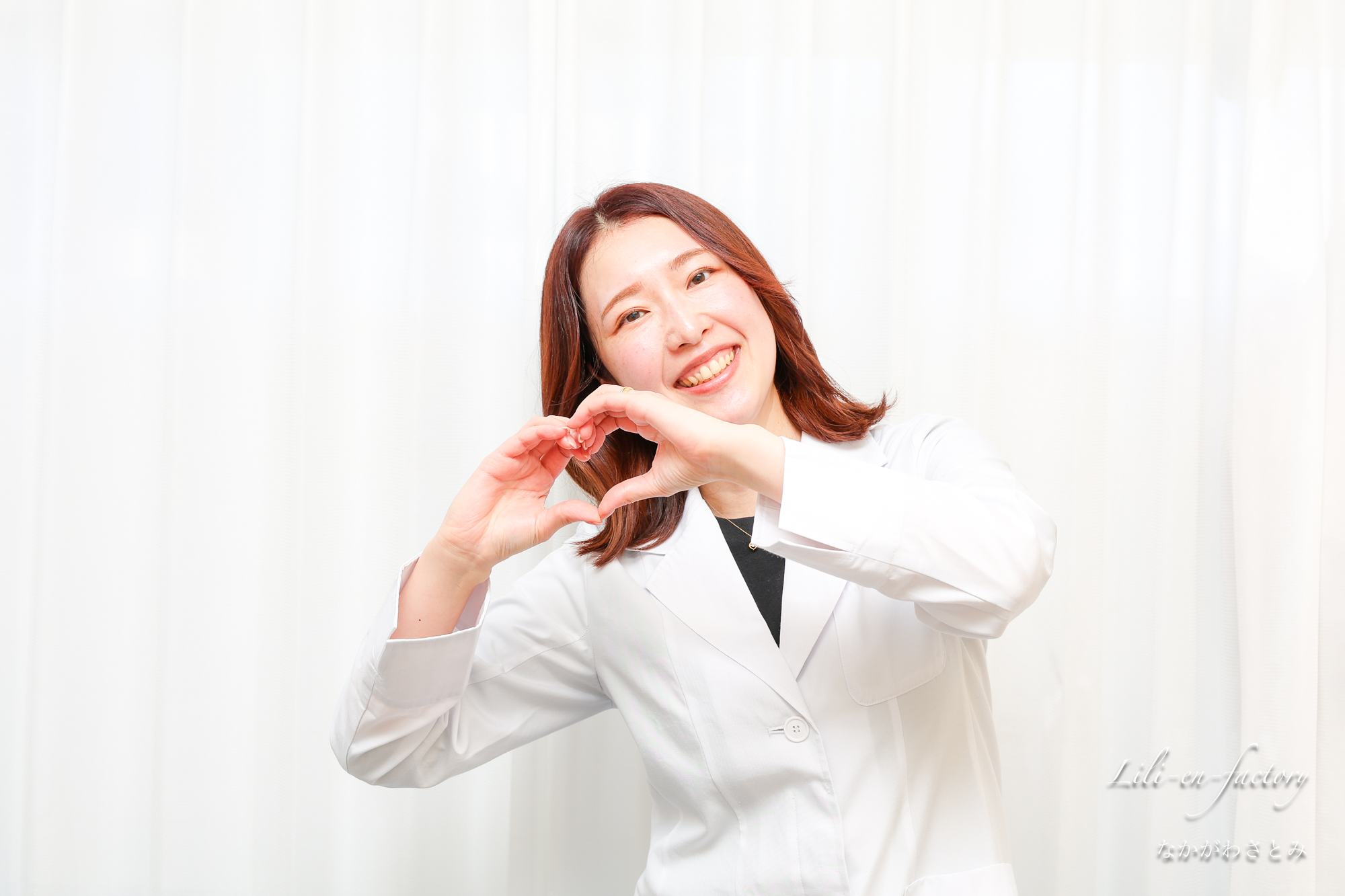 指でハートを作る白衣の女性